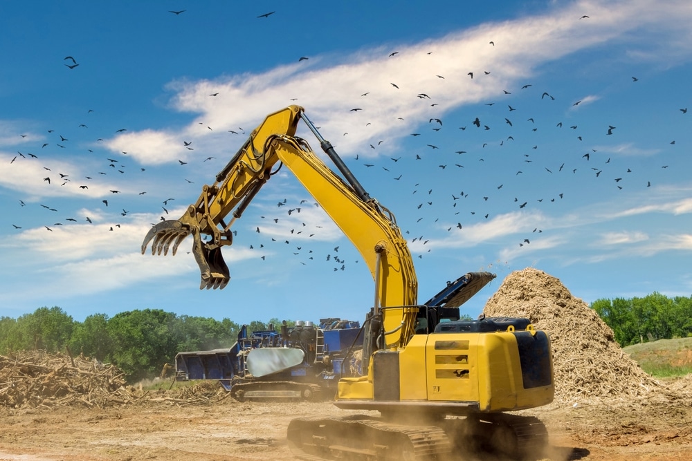crane,holding,and,loading,roots,wood,into,a,chipper,shredder